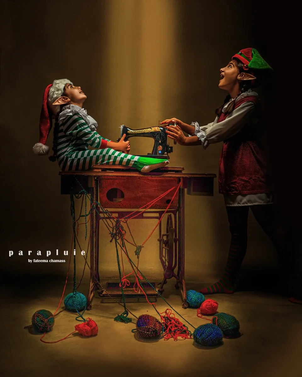 Children dressed as Christmas elves playing with a sewing machine and colorful yarn, festive holiday photoshoot at Parapluie Studio Lebanon.