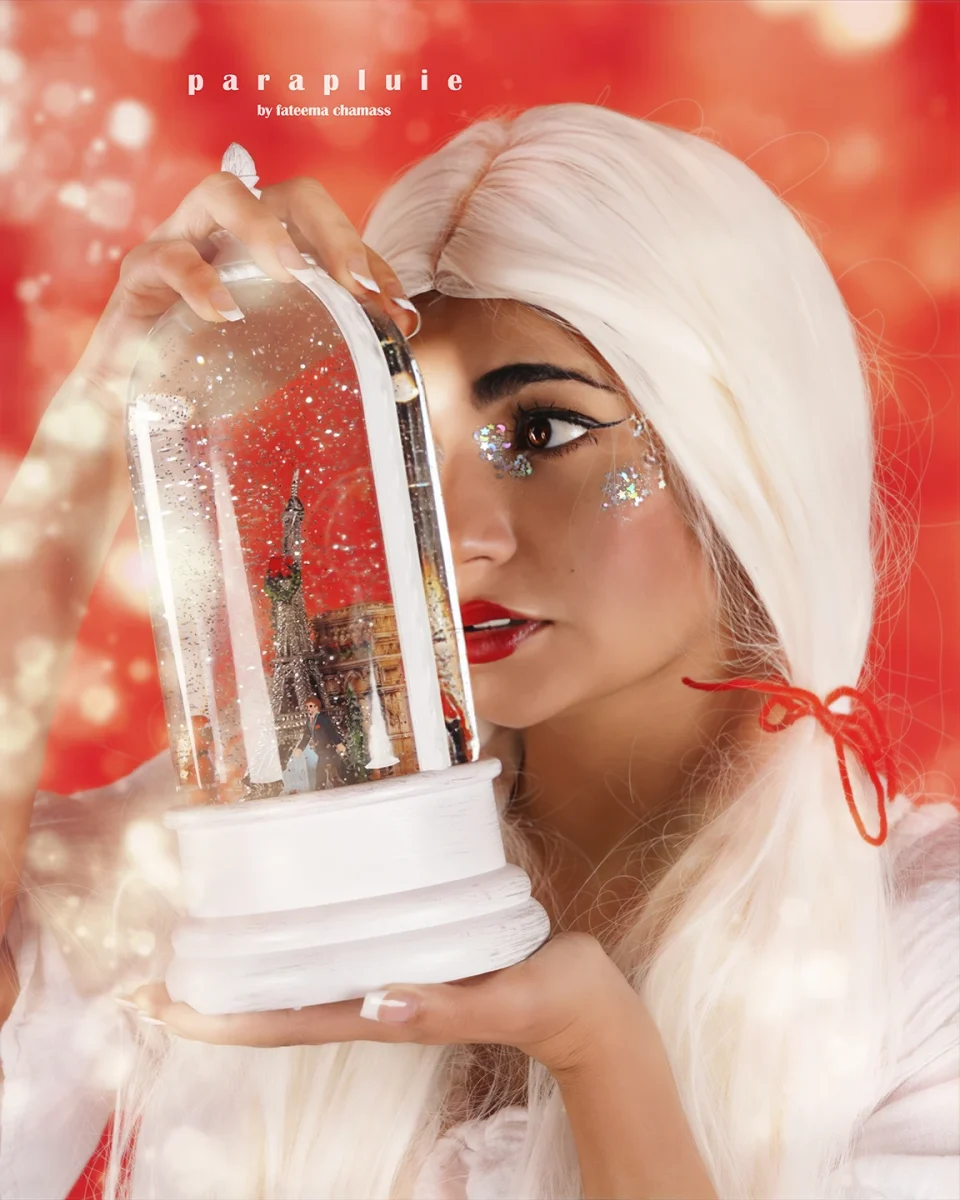 Lebanese influencer Jana Meer holding a snow globe in a conceptual fashion photoshoot with white hair and glitter makeup at Parapluie Studio.