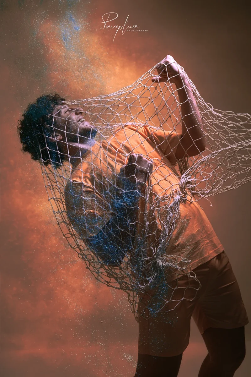 Lebanese influencer Karim Wazzan in a creative fashion photoshoot wrapped in a fishing net with dramatic powder effects at Parapluie Studio.