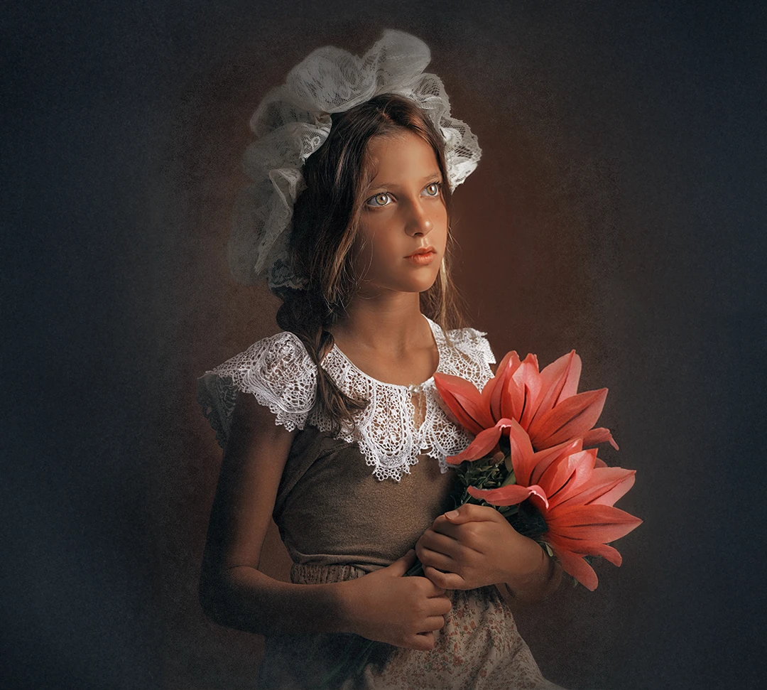 Young girl in vintage lace bonnet and dress holding large red flowers, fine art children’s portrait at Parapluie Studio Lebanon.