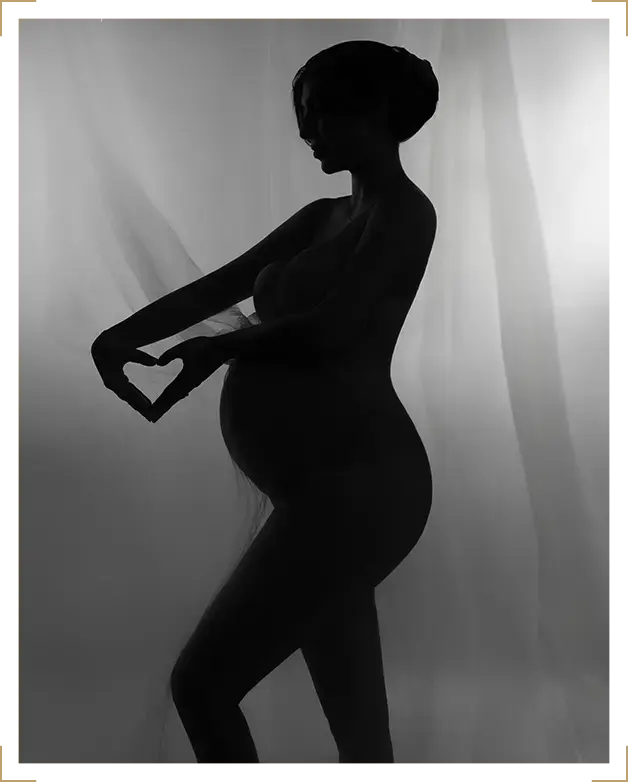 Silhouette of pregnant woman making a heart shape with her hands, artistic black and white maternity photoshoot at Parapluie Studio Lebanon.